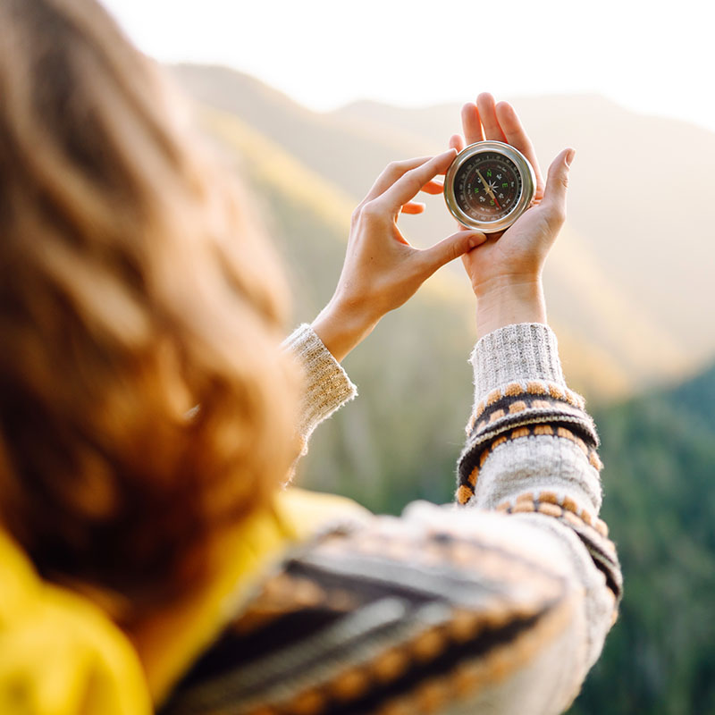 Back view of a woman holding up her hands, holding a compass